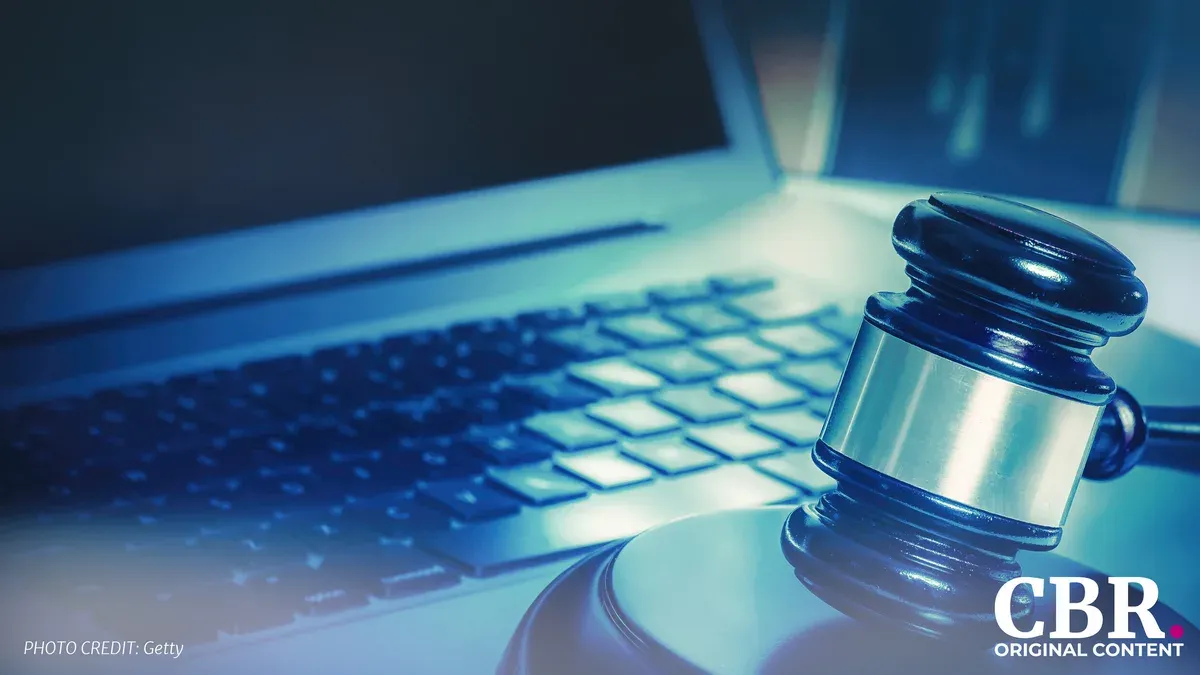 A judge's gavel resting on an open laptop keyboard, lit in blue