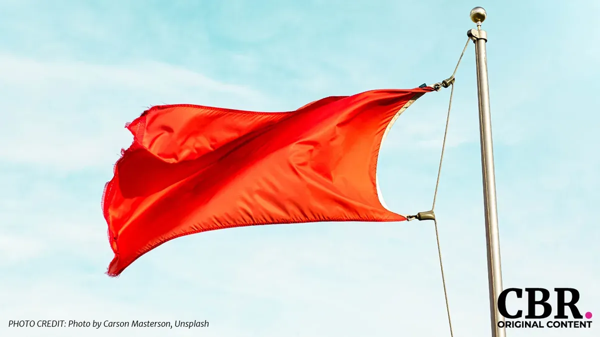 A red flag waving against a blue sky