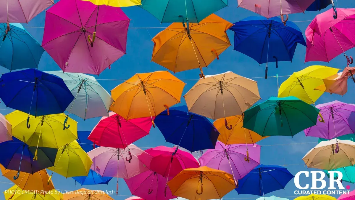 Rows of brightly colored open umbrellas hanging against a blue sky