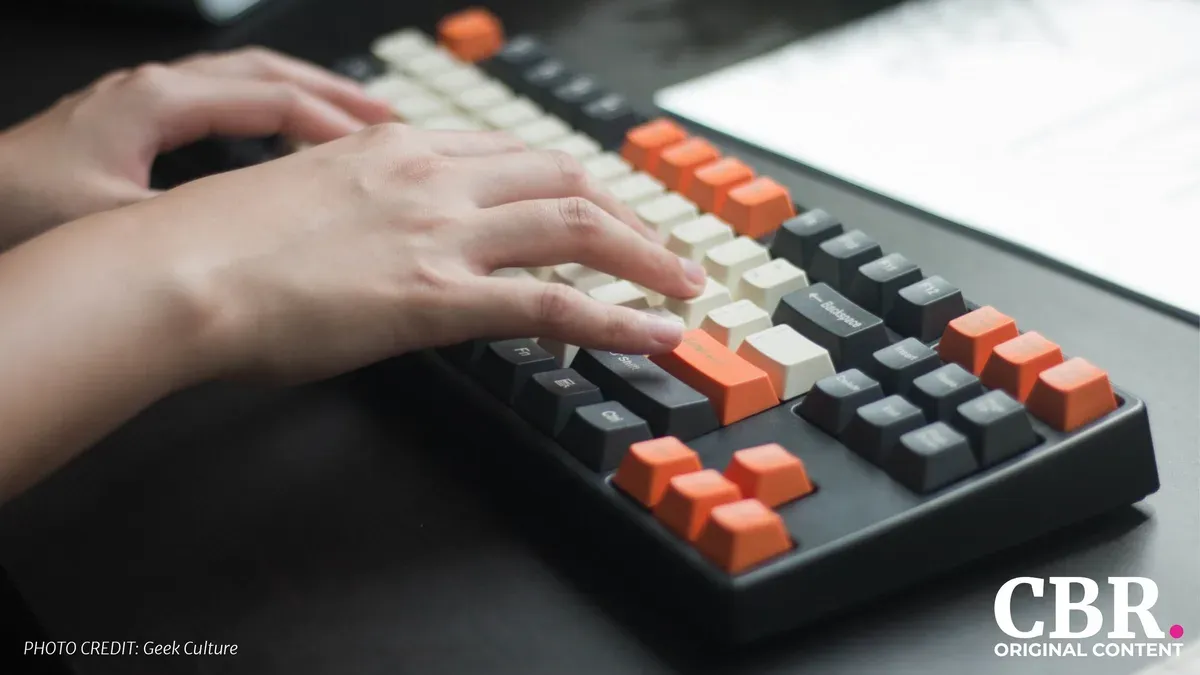 Close-up of hands typing on a mechanical keyboard with orange and cream keycaps