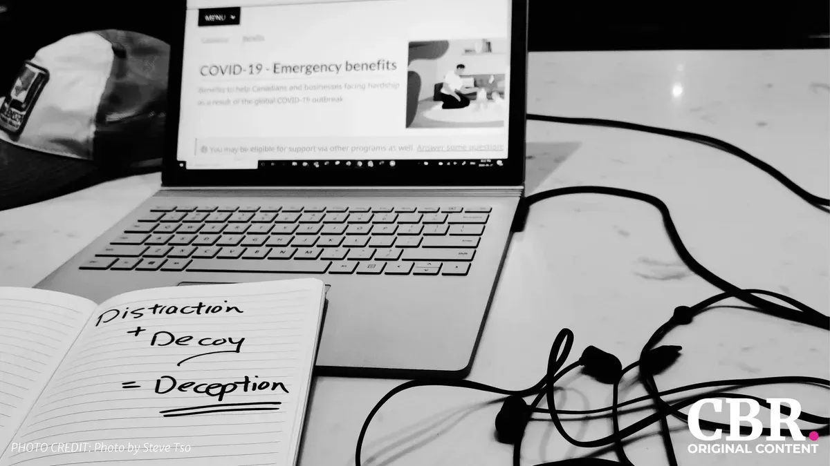 A handwritten notebook page reading Distraction plus Decoy equals Deception, next to a laptop, in black and white