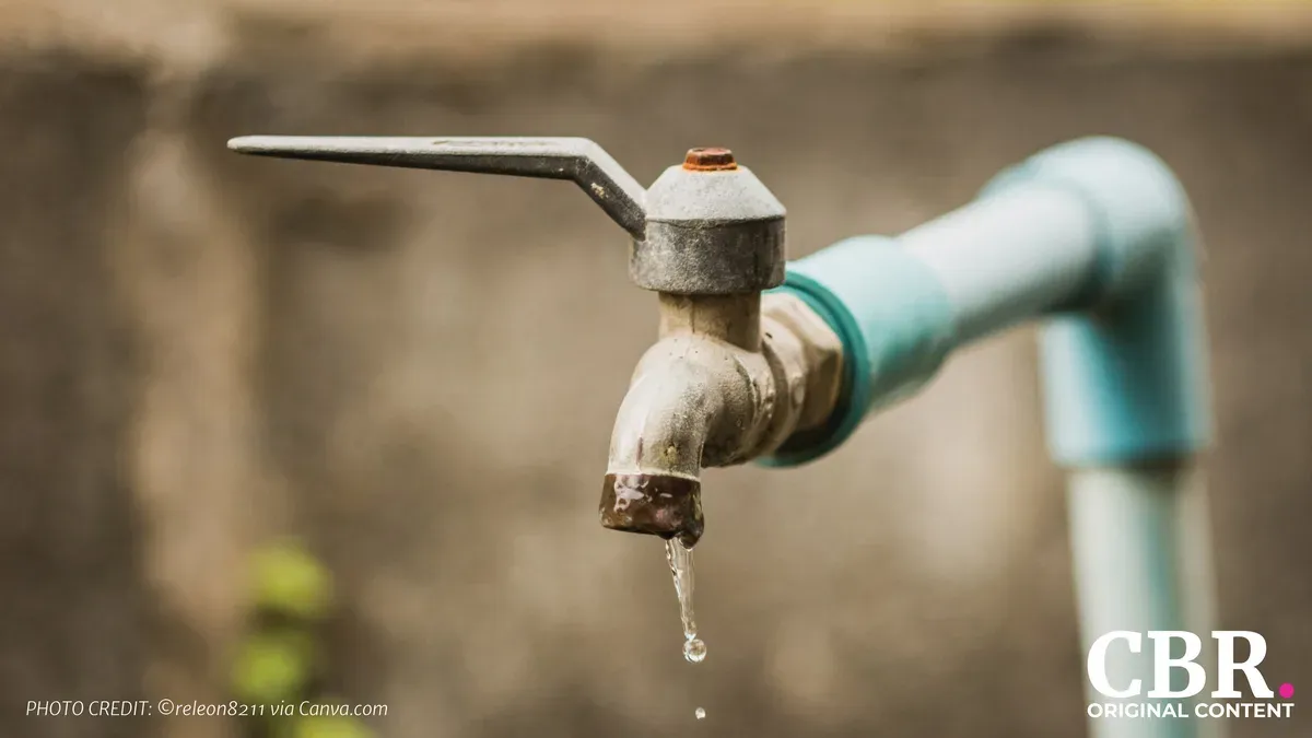 A close-up of an outdoor water tap with a droplet falling